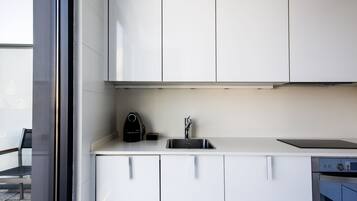 Una cocina moderna con armarios blancos, un lavamanos de acero inoxidable y un horno empotrado.
