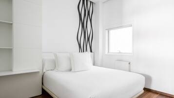 A modern bedroom with a bed, white walls, a window, and a radiator.