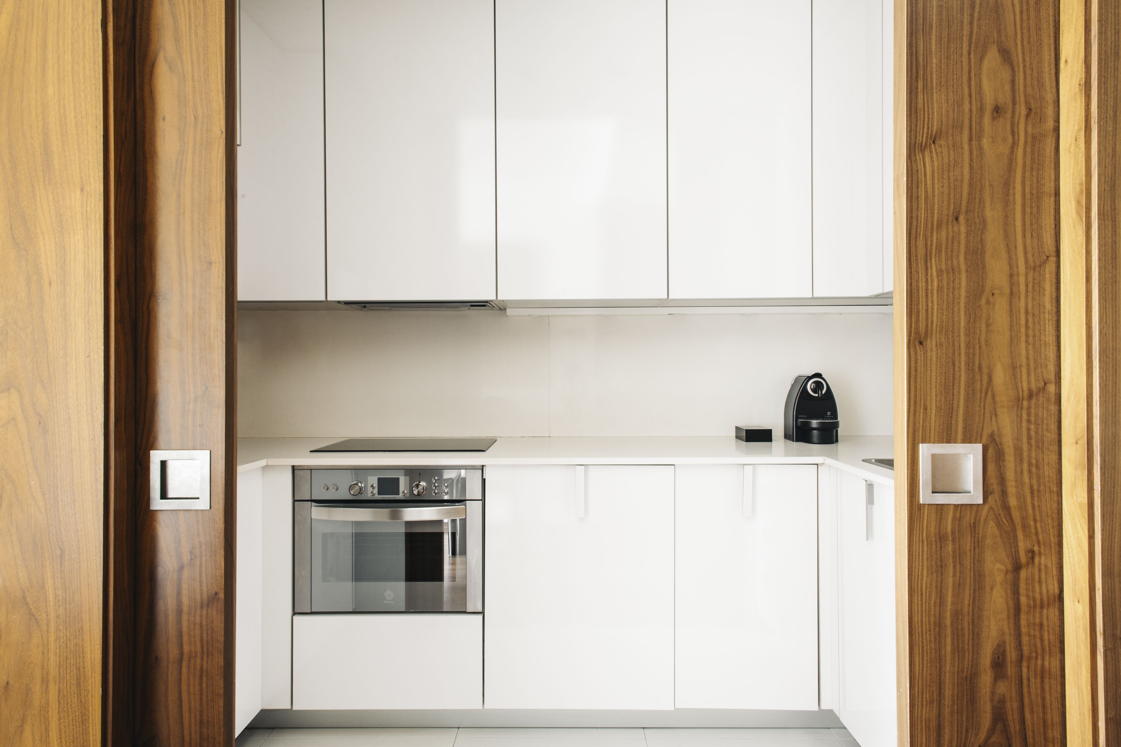 Una cocina moderna con armarios blancos, electrodomésticos de acero inoxidable y un marco de puerta de madera.