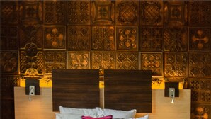 A neatly made bed with a striped duvet, pillows, and a folded towel. - Au Grand Hôtel de Sarlat (Sarlat-la-Canéda)