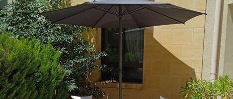 A patio with two wicker sofas, a small table, and an umbrella.