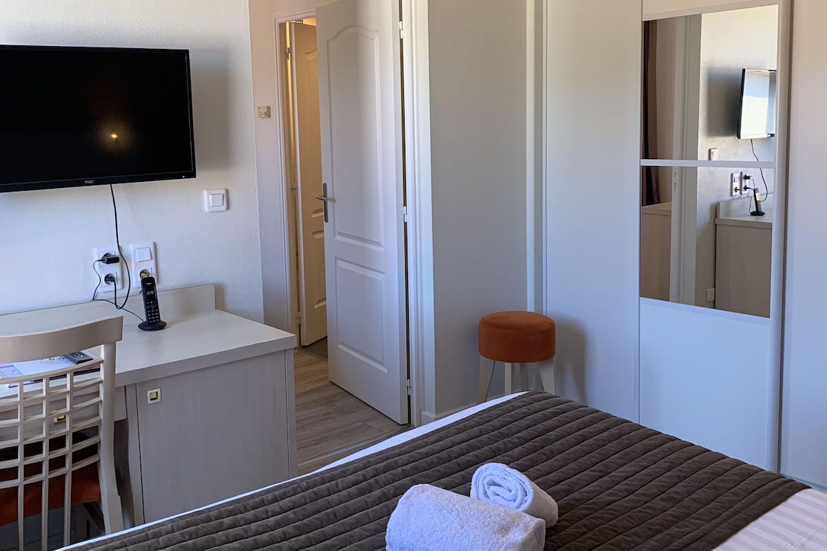 A hotel room with a bed, a desk, a TV, and a wardrobe.