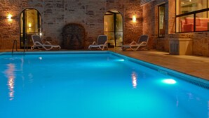 A swimming pool with lounge chairs, stone walls, and a stone archway. - Au Grand Hôtel de Sarlat (Sarlat-la-Canéda)