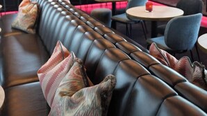 A modern bar area with a leather couch, round tables, and bar stools. - Van Der Valk Hotel Amersfoort A1 (Amersfoort)