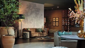 A modern living room with a sofa, coffee table, and decorative plants. - Van Der Valk Hotel Amersfoort A1 (Amersfoort)