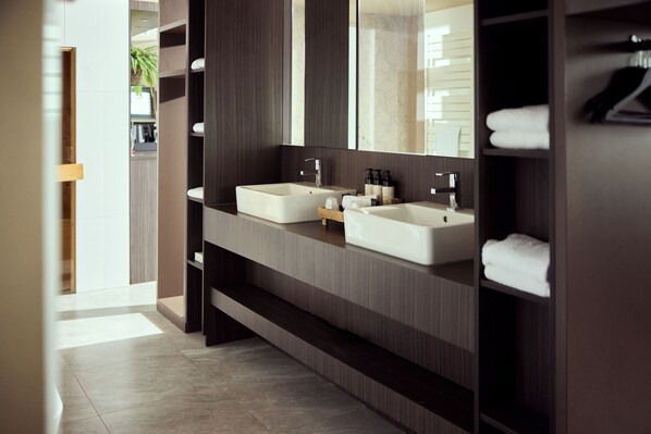 Un baño moderno con dos lavamanos, un espejo grande y un perchero para toallas.