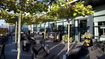 An outdoor seating area with wicker furniture, a bar area, and a building with large windows.