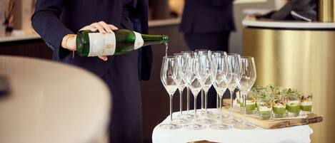 A person pouring champagne into a row of wine glasses on a table.