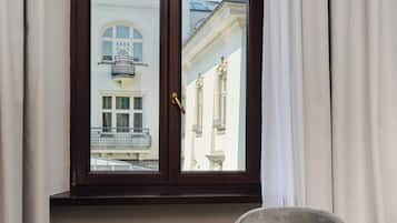 A room with a window, a radiator, a grey armchair, a table with a plate of food and a cup of coffee.