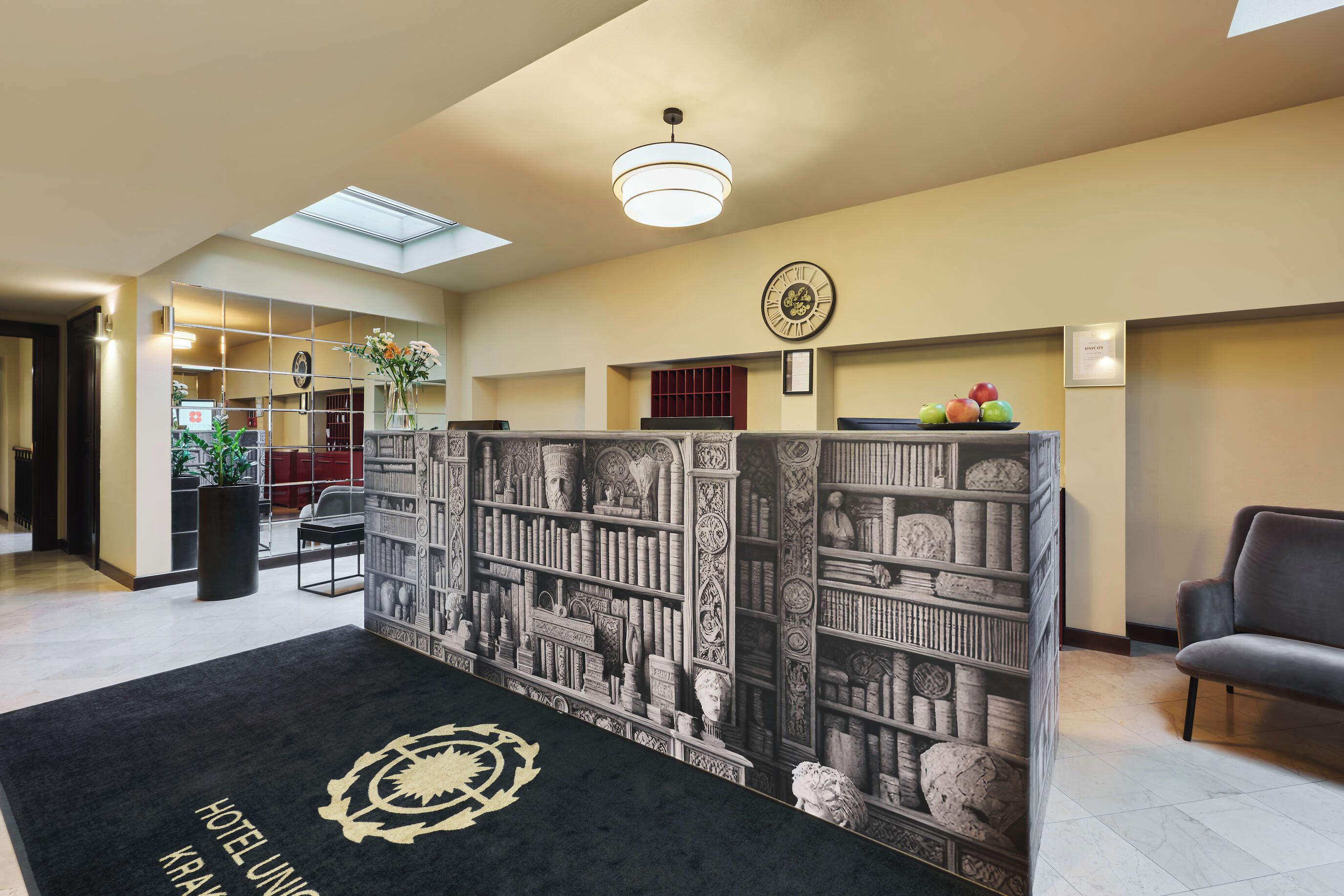 Et hotellobby med reception, et ur og en reol.