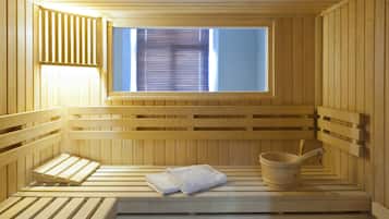Una sauna con bancos de madera, una ventana con persianas y un cubo de madera con asa.