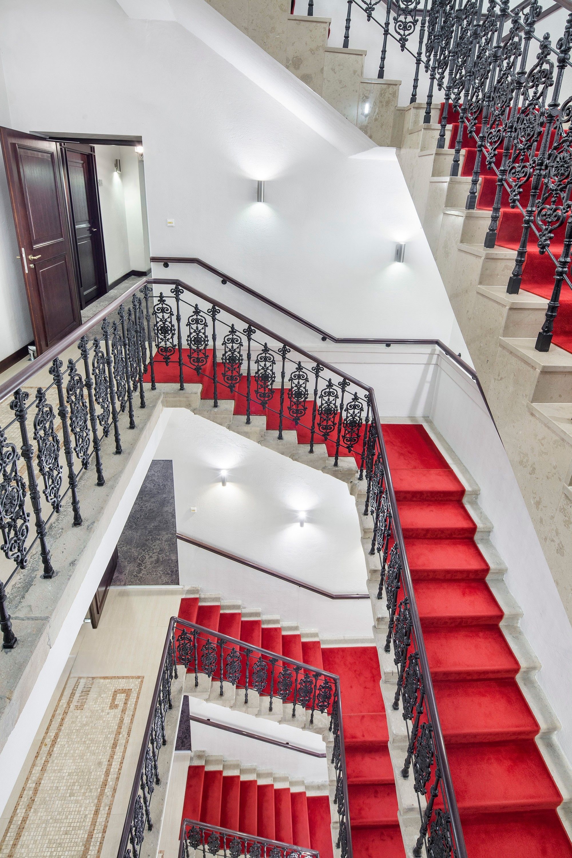A grand staircase with ornate black railings and red carpeted steps.