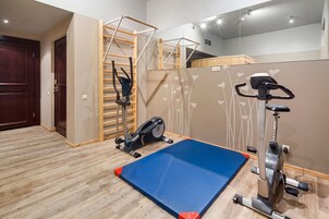 A gym with exercise equipment, a blue mat, and a wooden ladder.