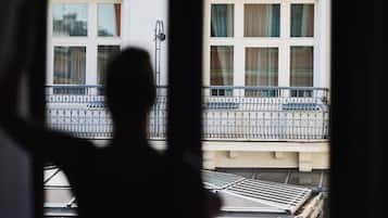 Silueta de una persona frente a un ventanal con vistas a un edificio con múltiples ventanas y balcones.