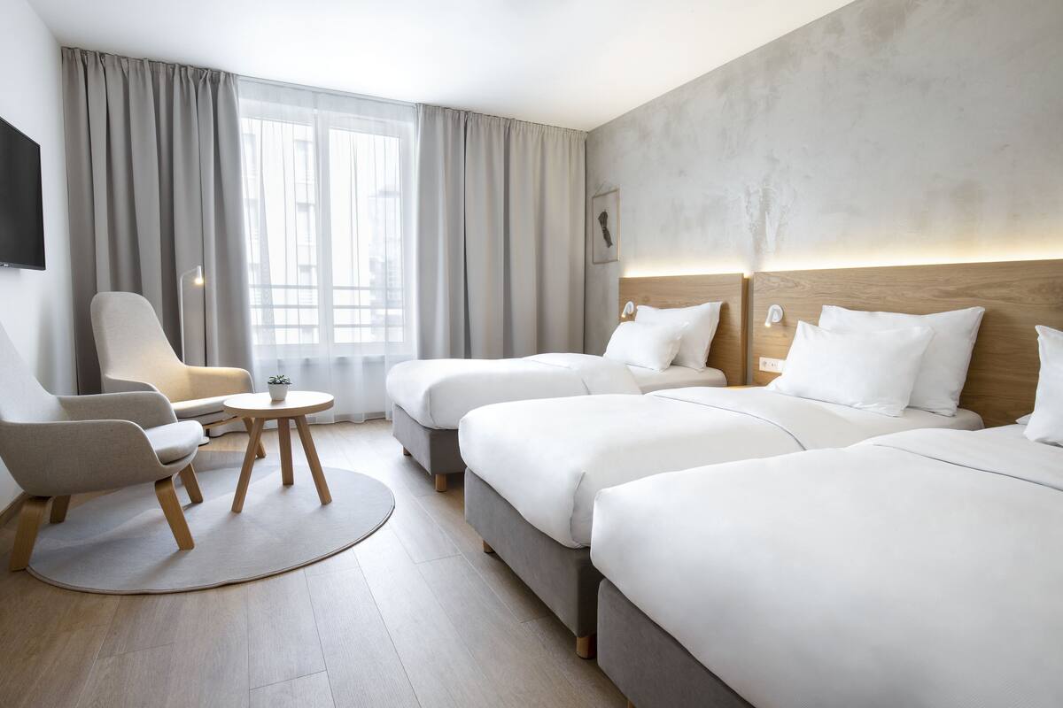A hotel room with a large bed, a sofa, a chair, and a small table.