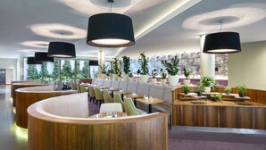 A modern restaurant with wooden furniture, black pendant lights, and potted plants. - Botanique Hotel Prague (Prague)