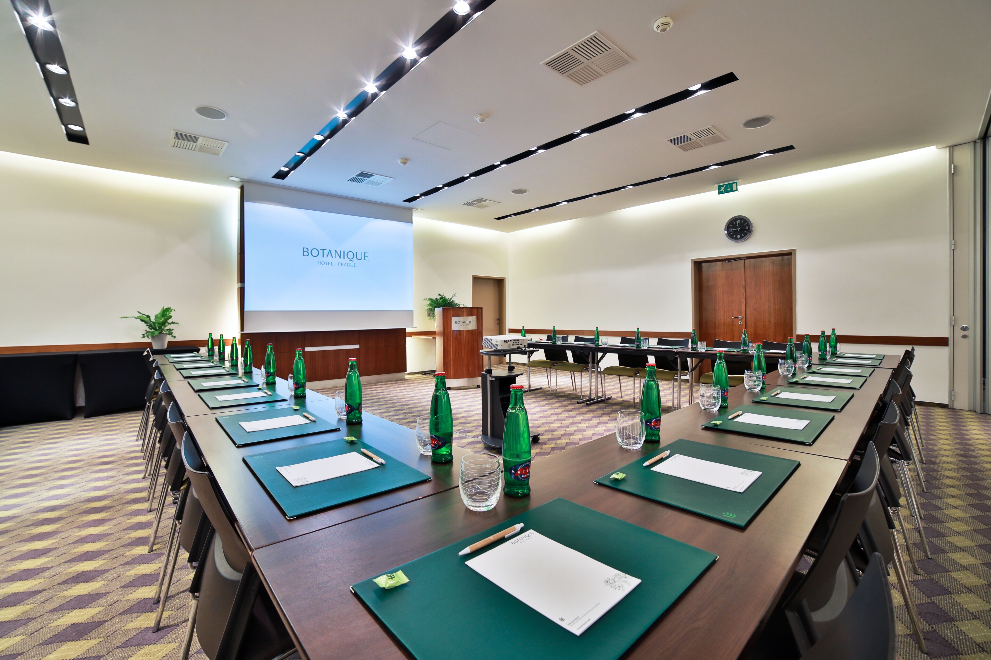 A conference room with a long table, chairs, and a projector screen displaying "BOTANIQUE HOTEL PARIS".