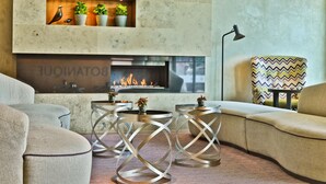 A modern living room with a fireplace, comfortable seating, and decorative plants. - Botanique Hotel Prague (Prague)