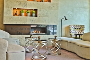 Uma sala de estar moderna com lareira, assentos confortáveis e plantas decorativas.