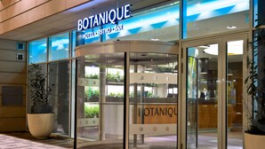 The exterior of the Botanique Hotel Bistro Bar with a glass entrance and large potted plants. - Botanique Hotel Prague (Prague)