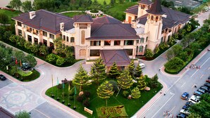 A large, multi-story building with a central courtyard, surrounded by trees and a golf course. - Chateau Star River (Beijing)