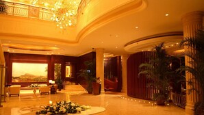 A spacious lobby with a grand chandelier, a reception desk, and a seating area with sofas. - Chateau Star River (Beijing)