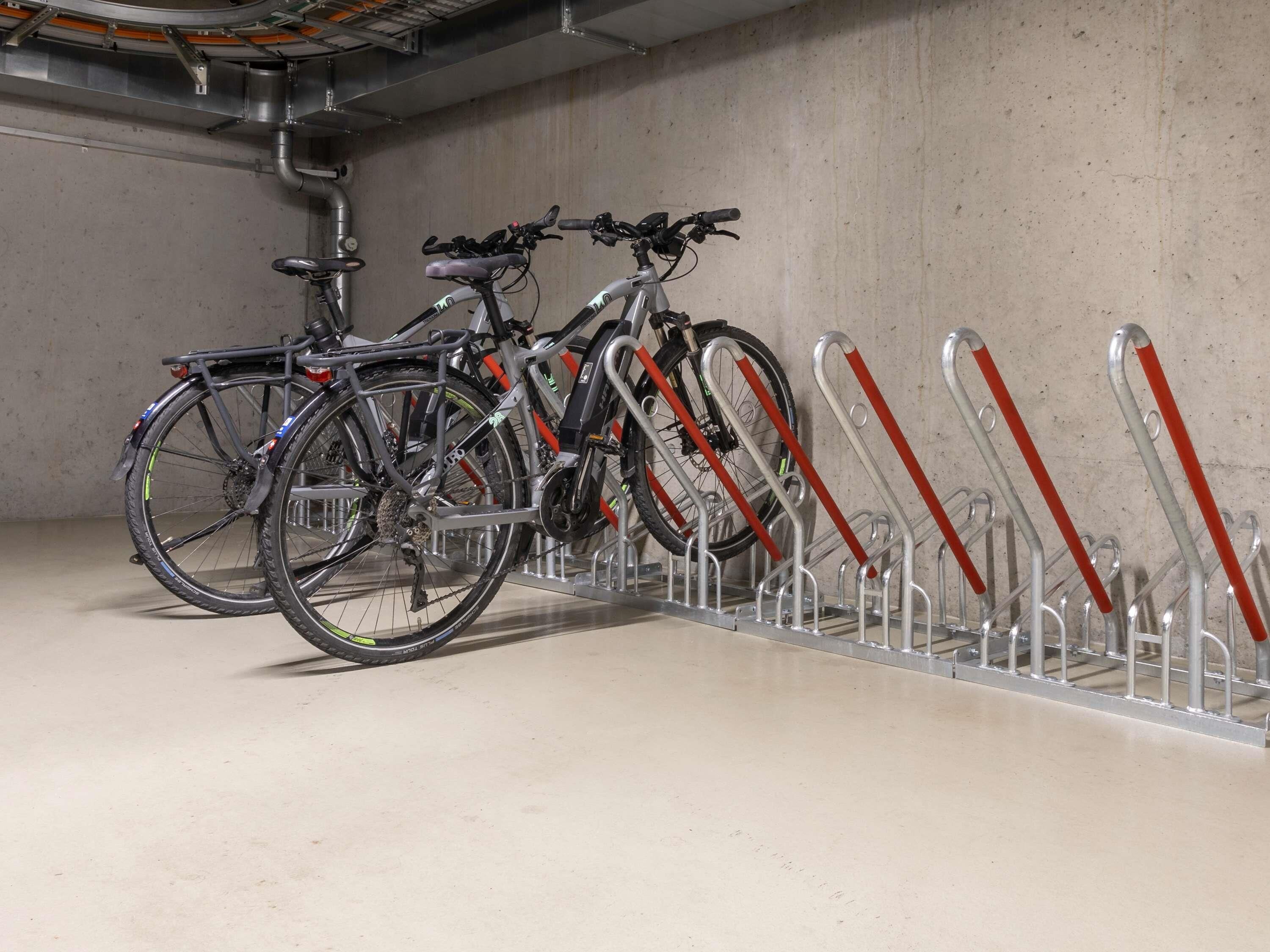 A bicycle parking area with metal racks and a concrete floor.