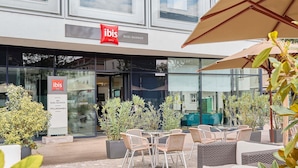An outdoor seating area with wicker furniture and potted plants at the ibis hotel. - ibis Basel Bahnhof (Basel)