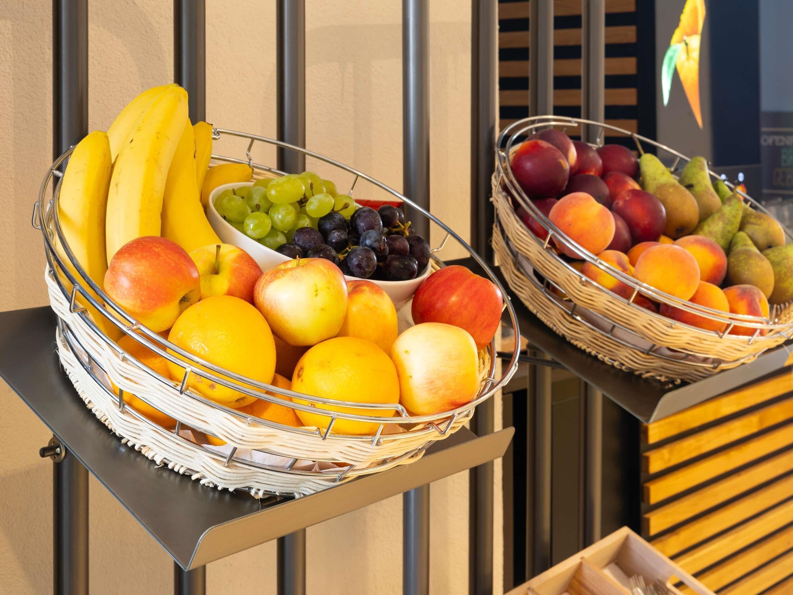 Twee rieten manden met fruit op een metalen standaard.