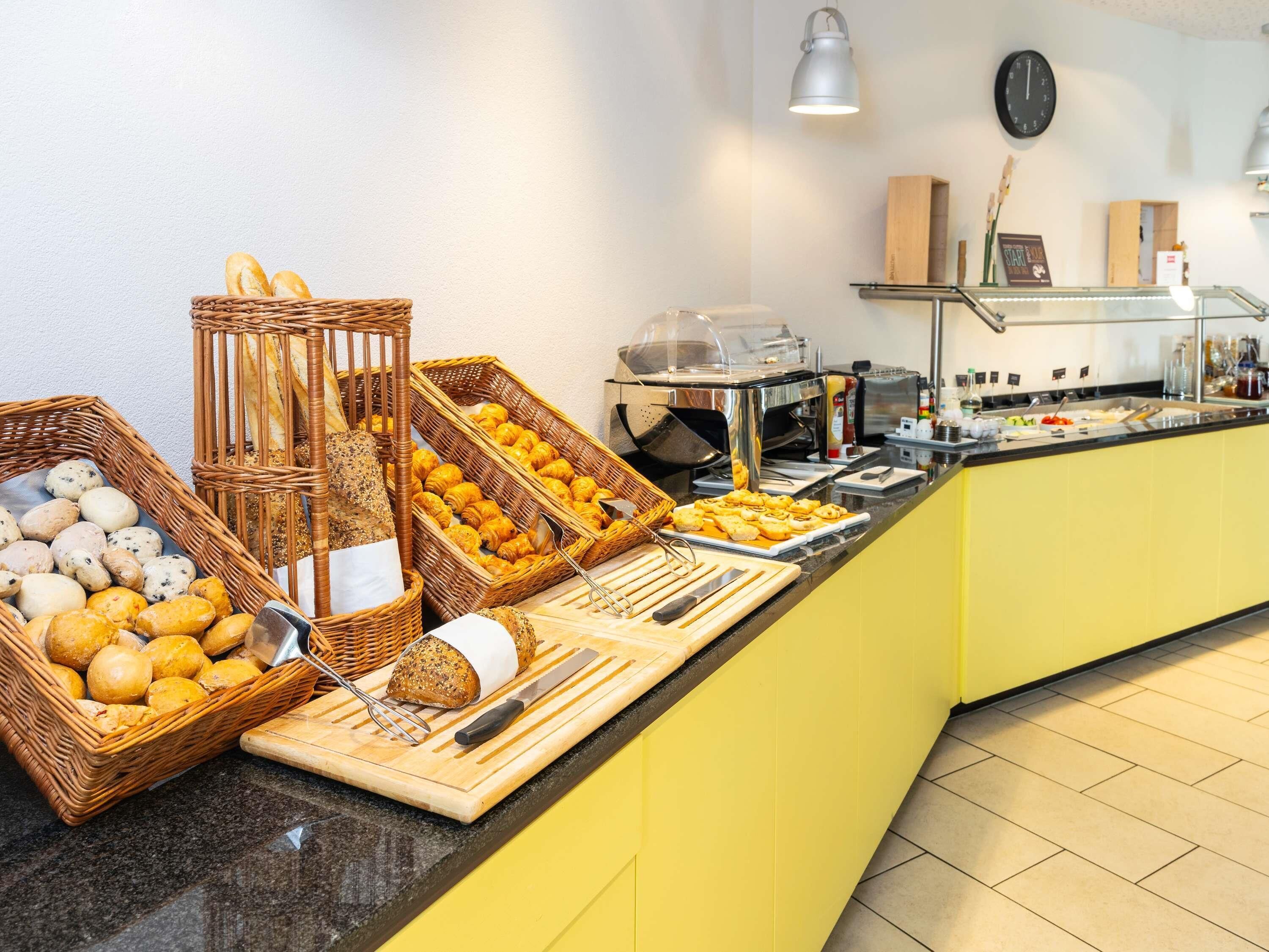 Un bufé de desayuno con panes, pasteles y una estación de café.