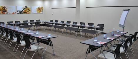A conference room with a long table, chairs, a whiteboard, and artwork on the walls.