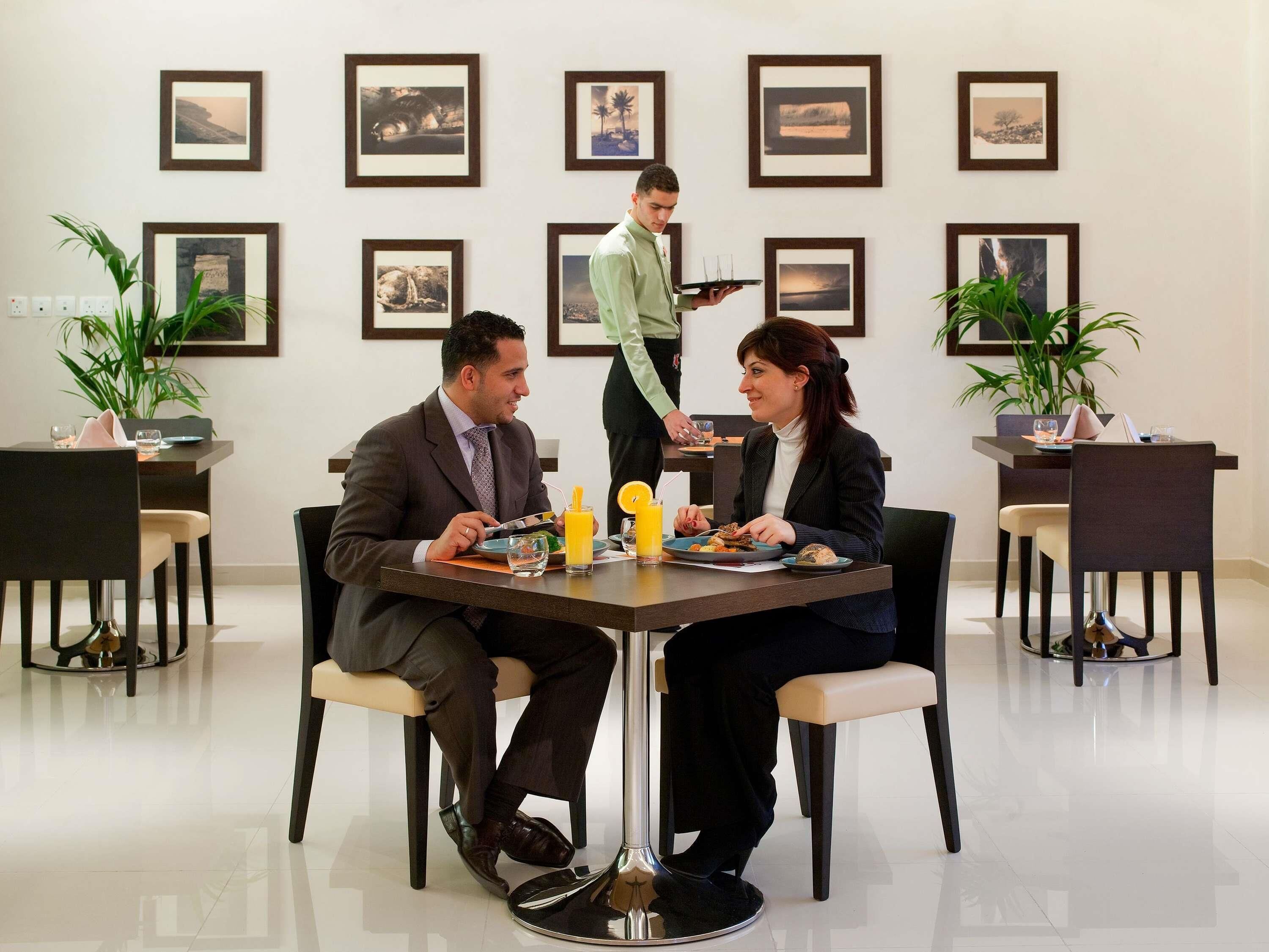 A dining area with a table, chairs, and framed pictures on the wall.