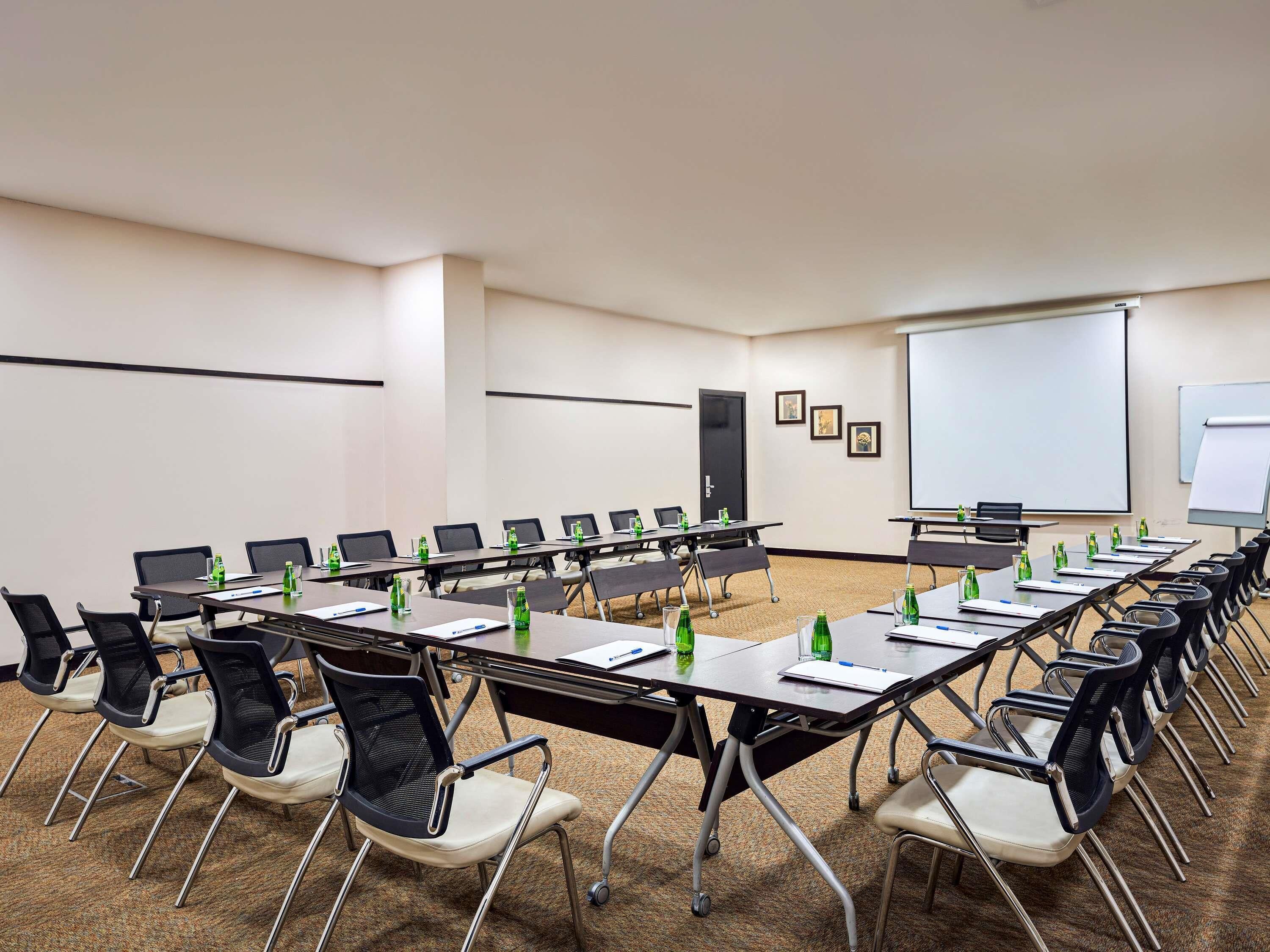 A conference room with multiple tables, chairs, and presentation screens.