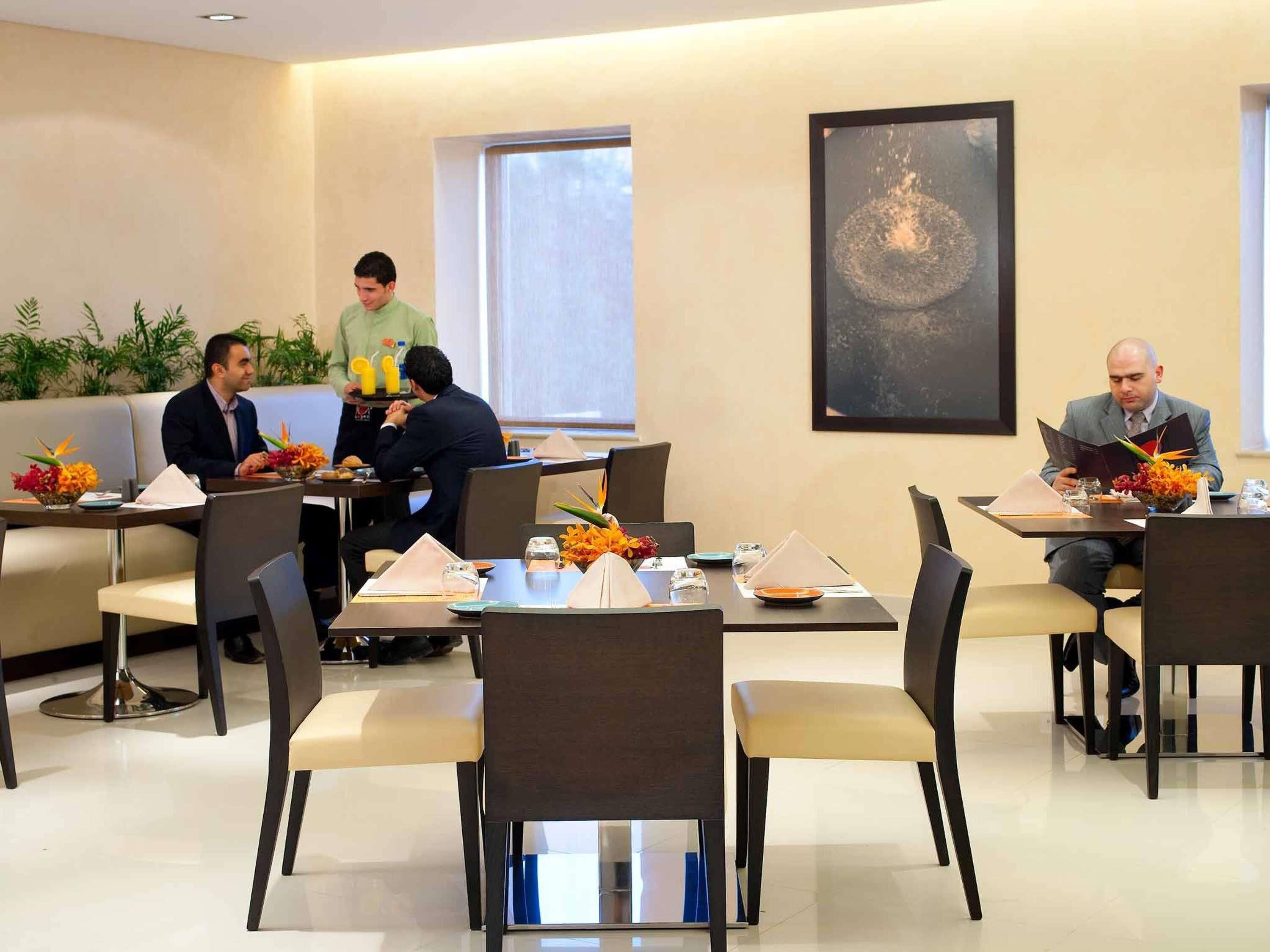 A dining area with tables, chairs, and a waiter.