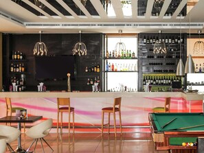 A bar area with a pool table, bar stools, and a variety of bottles on shelves. - ibis Amman (Amman)