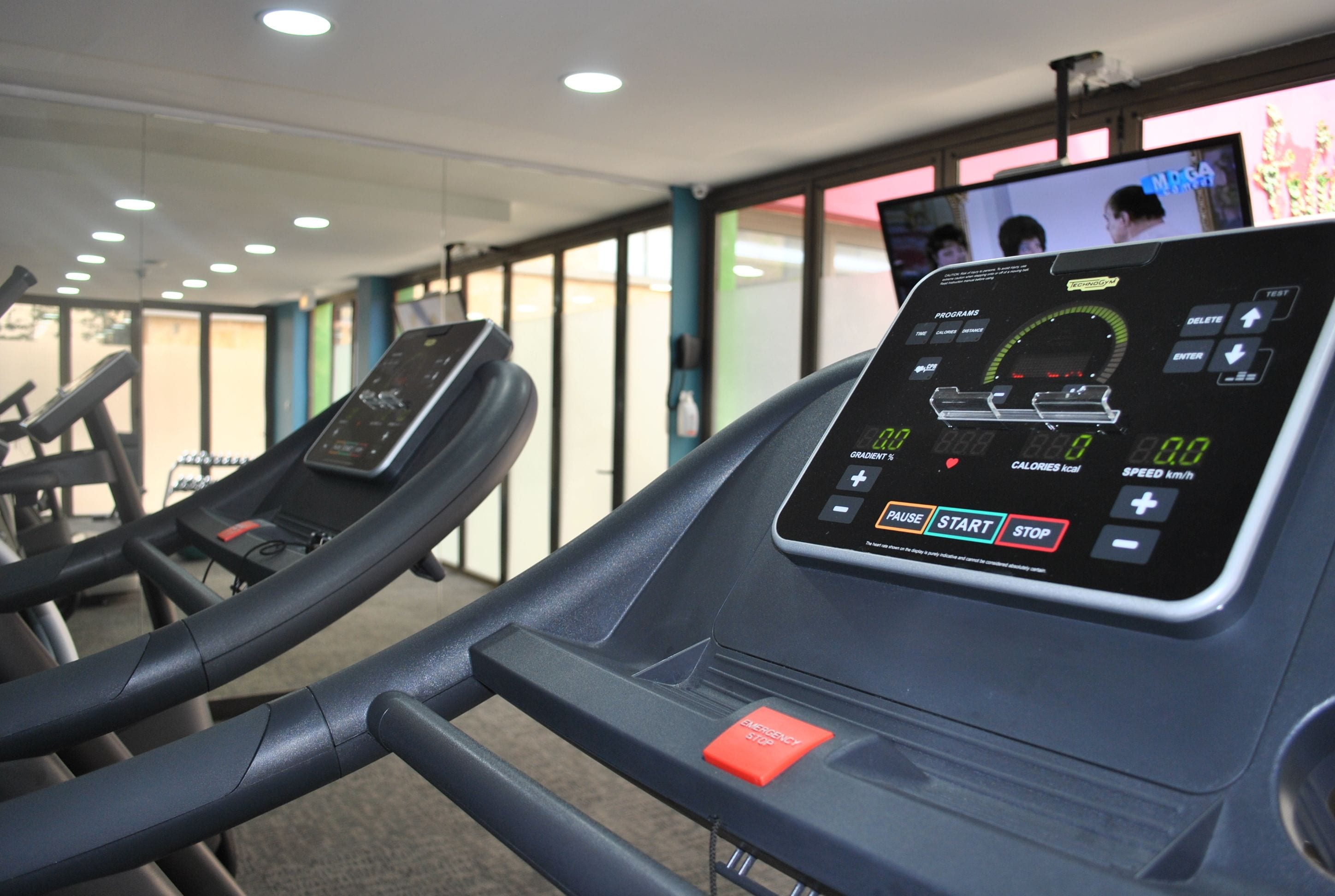Ein Fitnessstudio mit Laufbändern und einem digitalen Bildschirm, der Trainingsdaten anzeigt.