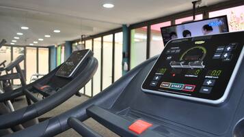 Un gimnasio con cintas de correr y una pantalla digital que muestra datos del entrenamiento.