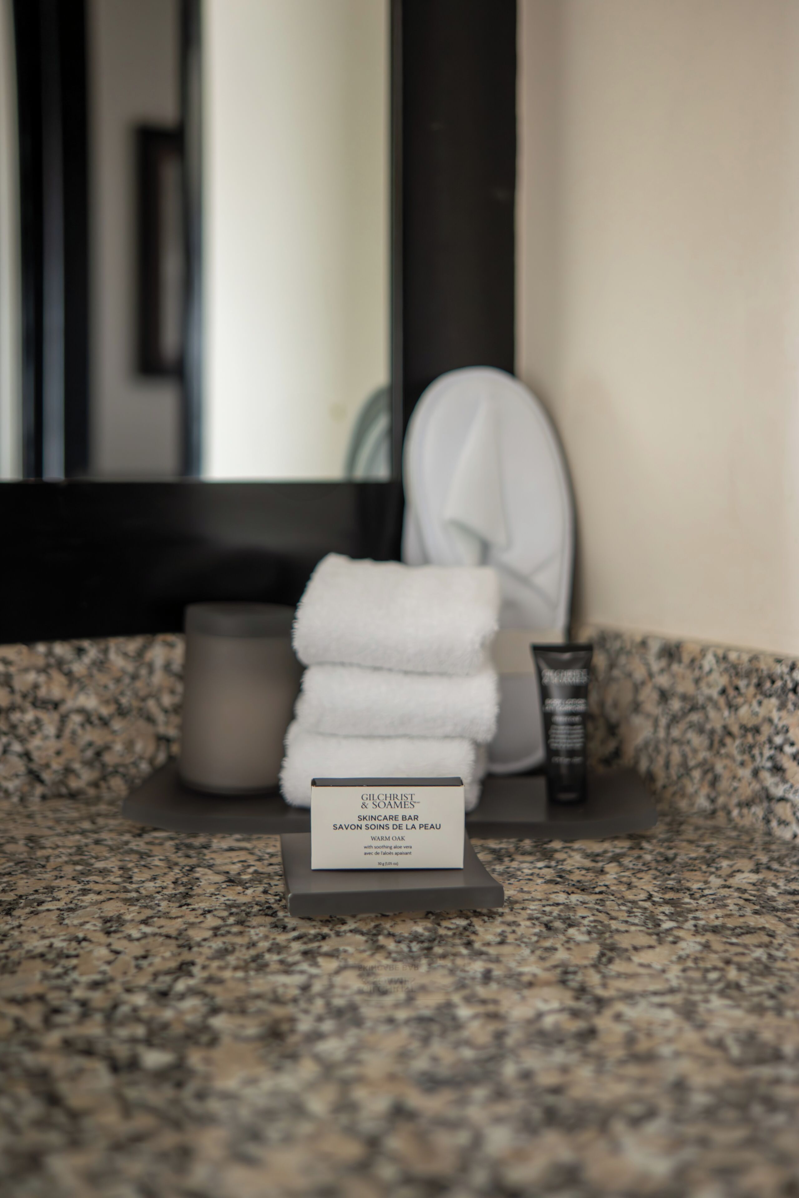 A bathroom counter with a skincare bar, a towel, and a cup.