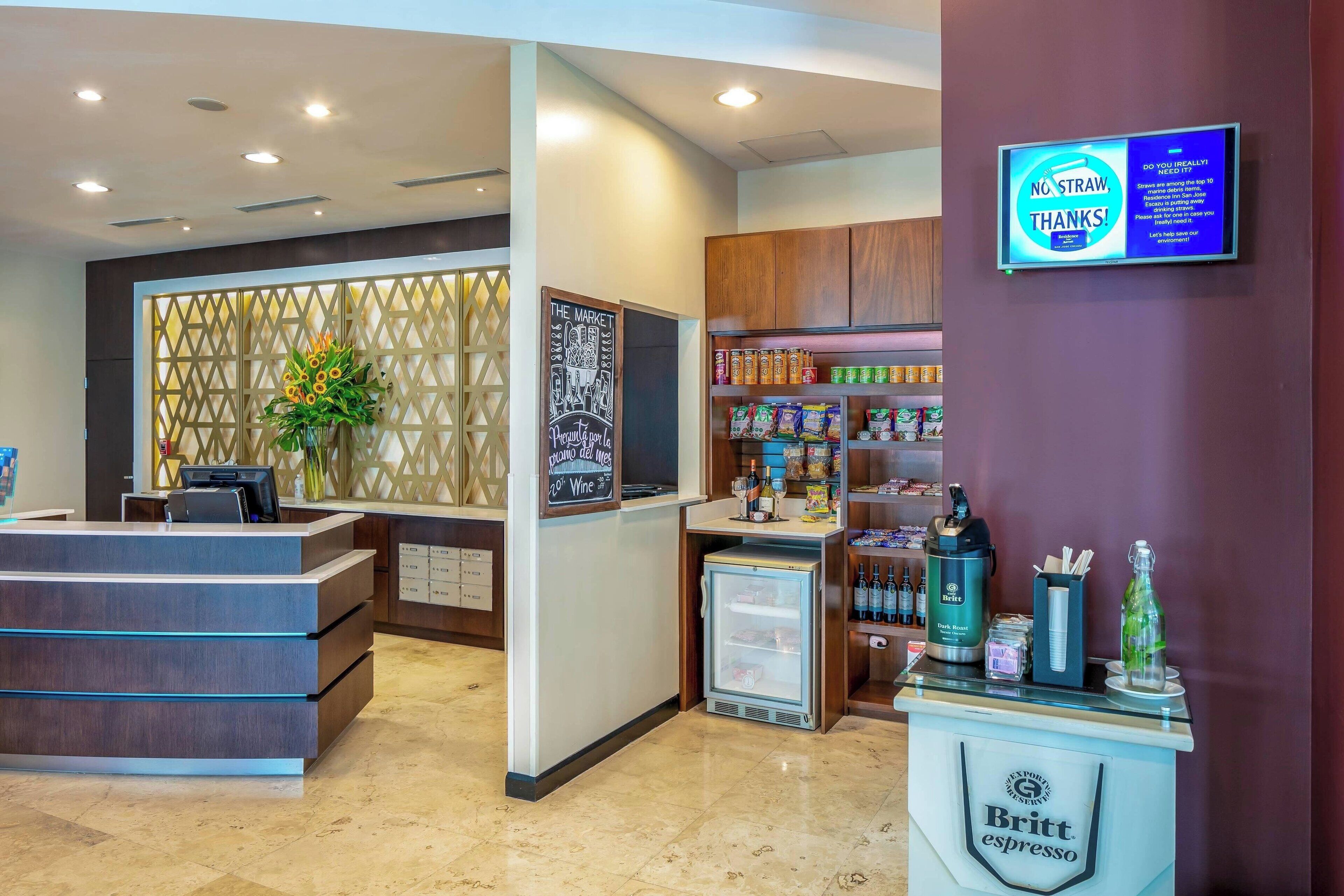 A reception area with a counter, a refrigerator, and a display of beverages.