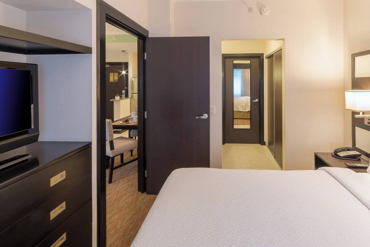 A hotel room with a bed, a desk with a chair, a television, and a telephone.