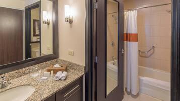 A bathroom with a granite countertop, a sink, a mirror, a shower with a glass door, and a towel rack.