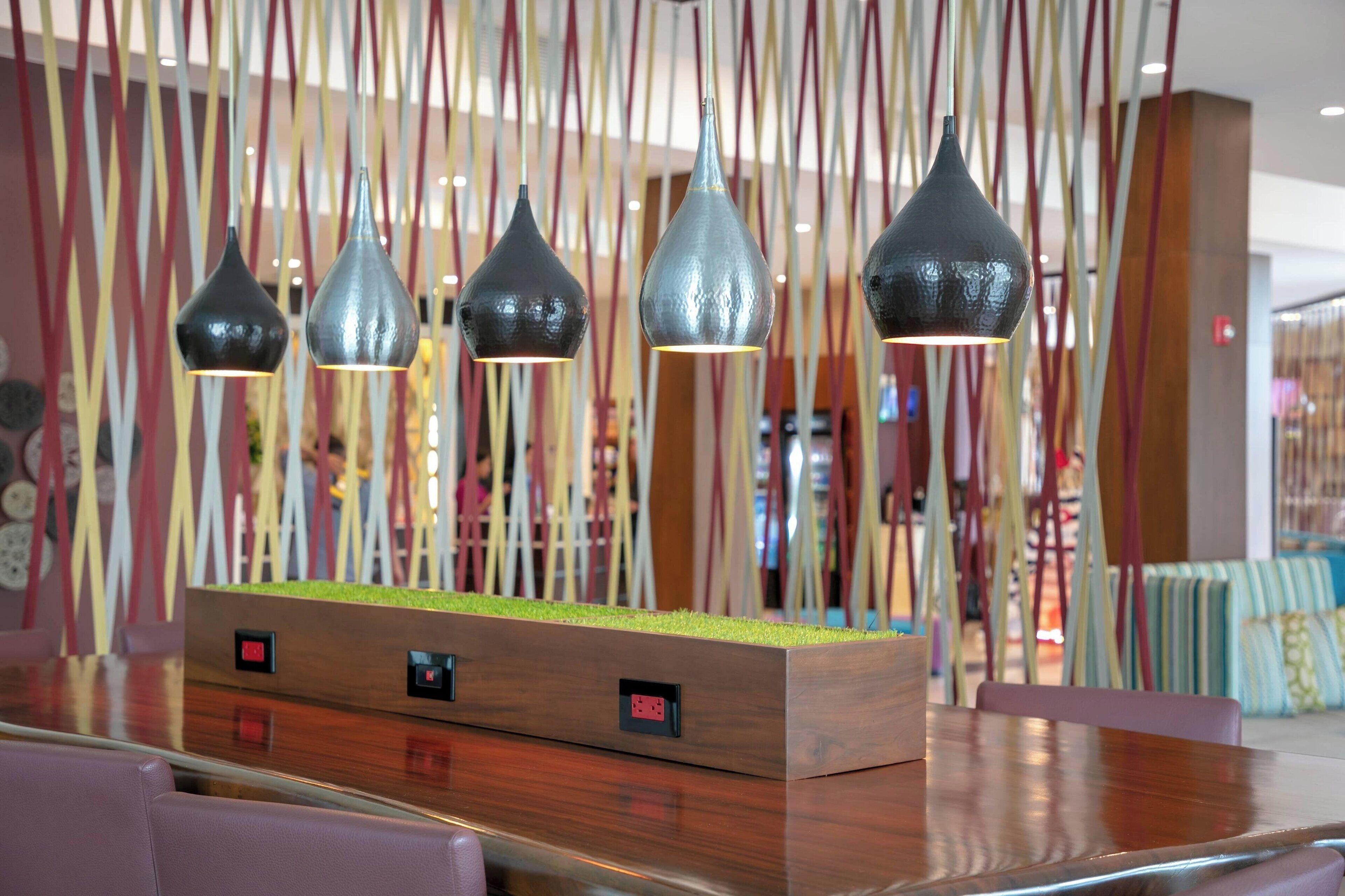 A modern interior with a wooden reception desk, a green plant, and hanging pendant lights.