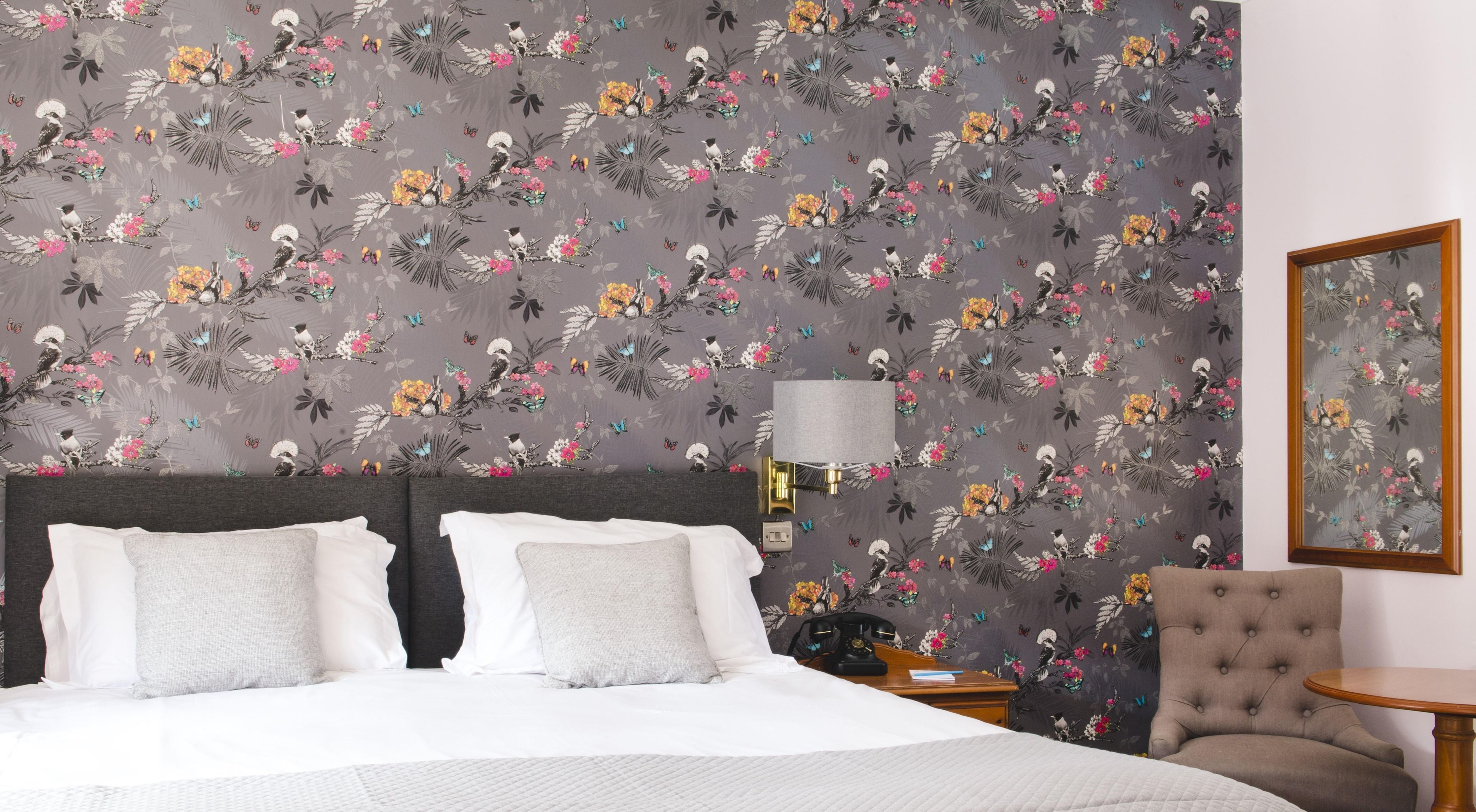Une chambre d’hôtel avec un grand lit, une table de chevet, une lampe, une chaise et un tableau encadré au mur.