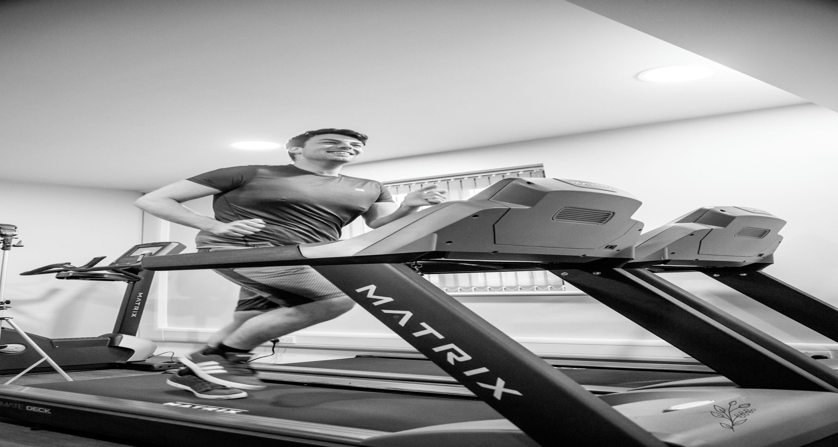 A person using a treadmill in a room with a window and a visible ceiling light fixture.