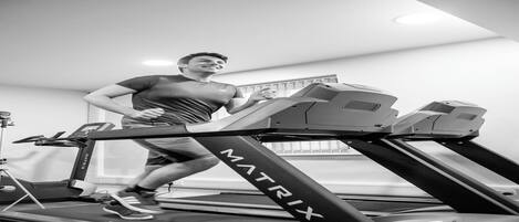 A person using a treadmill in a room with a window and a visible ceiling light fixture.