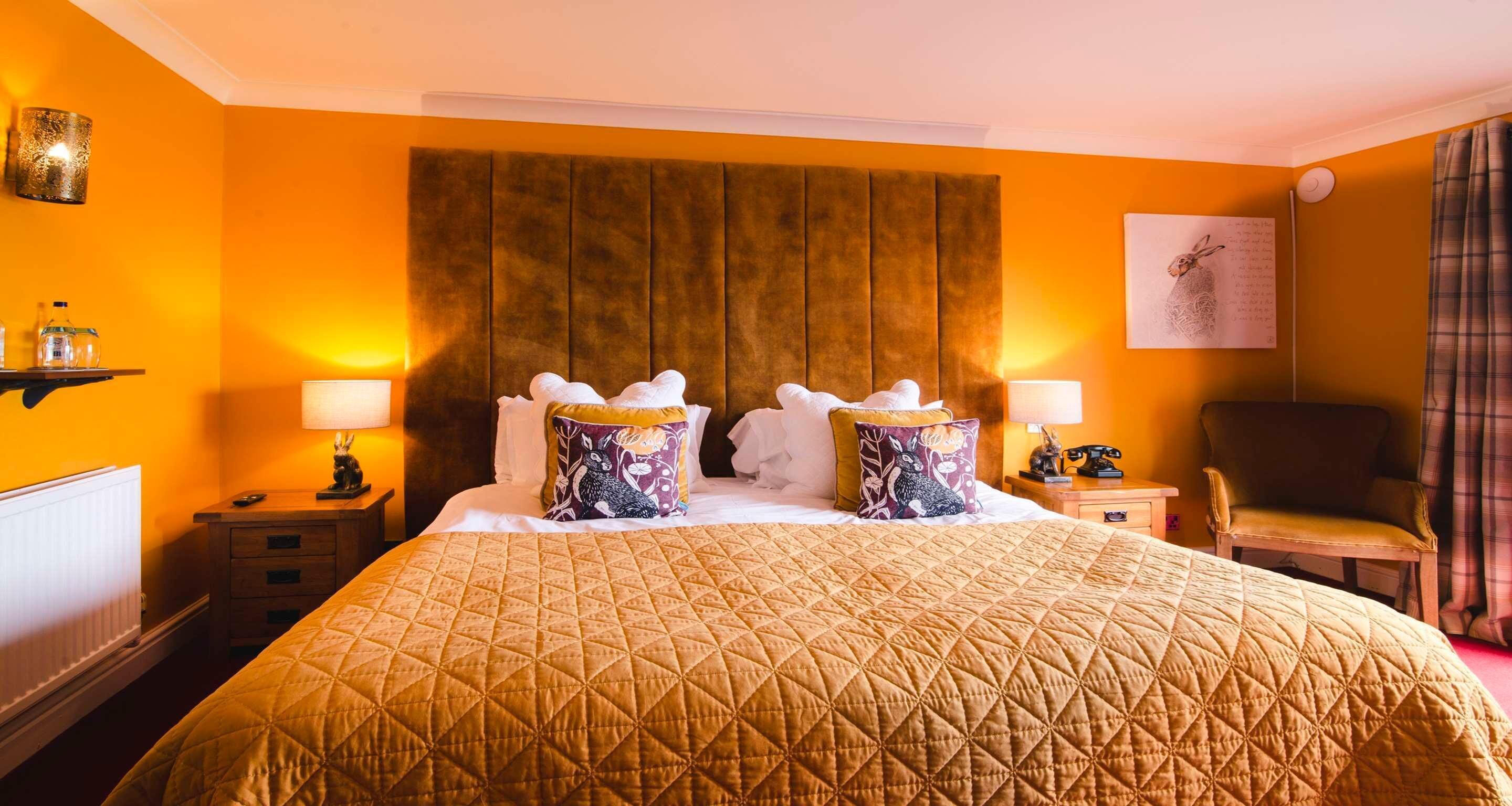 A hotel room with a large bed, two bedside tables, a chair, a wall-mounted lamp, and a radiator.