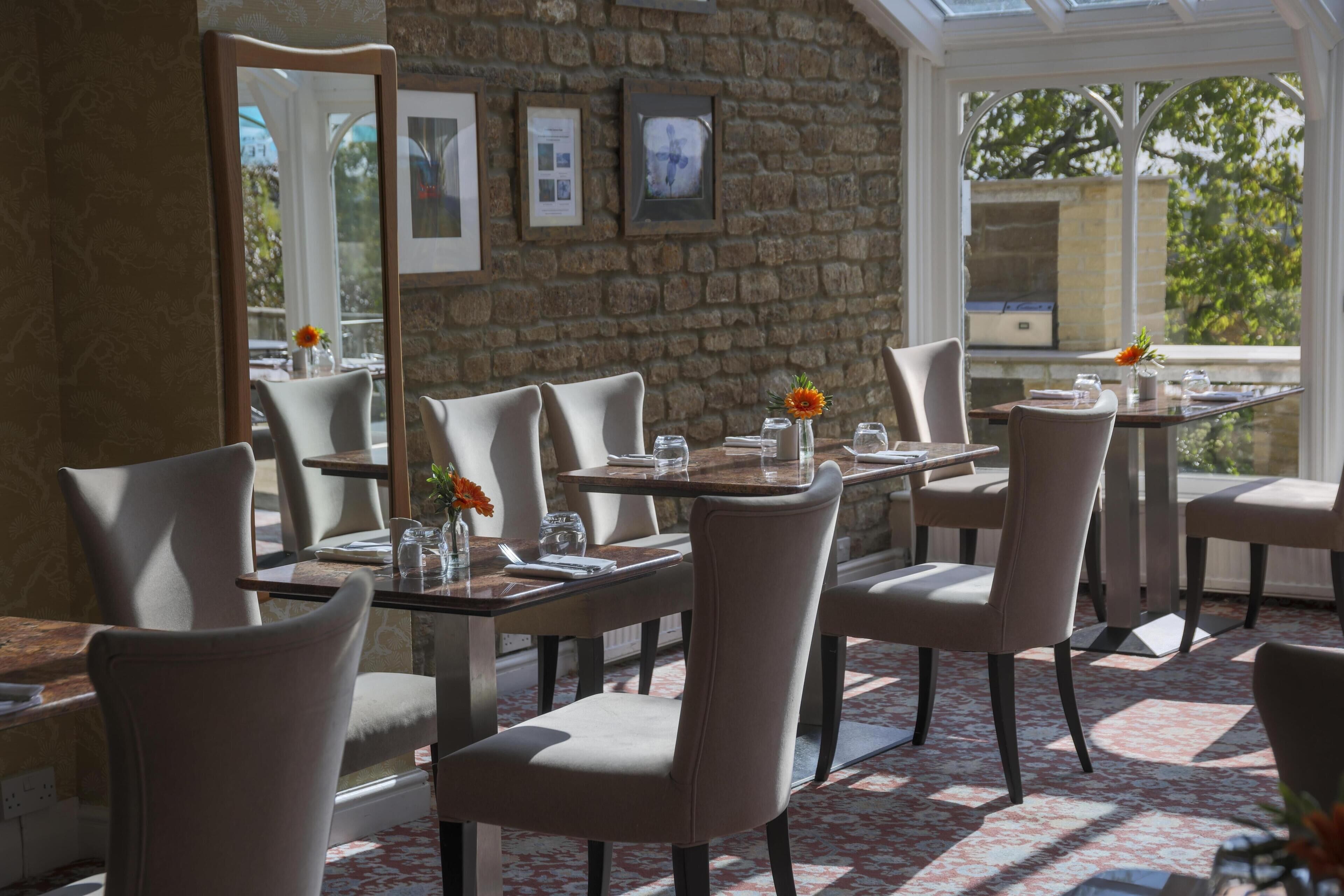 Ein Restaurant mit Steinwänden, gerahmten Bildern und Blick auf Grünflächen.