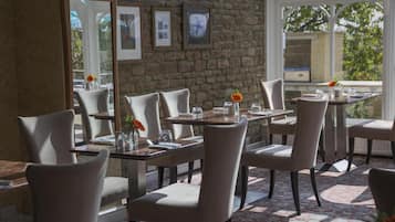 Ein Restaurant mit Steinwänden, gerahmten Bildern und Blick auf Grünflächen.