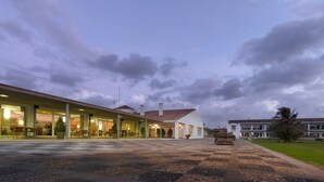 A hotel with a covered outdoor seating area, a tiled courtyard, and a building with a tiled roof.