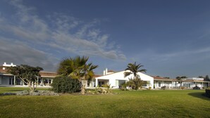 A modern house with a white exterior, a covered patio, and a well-maintained lawn.